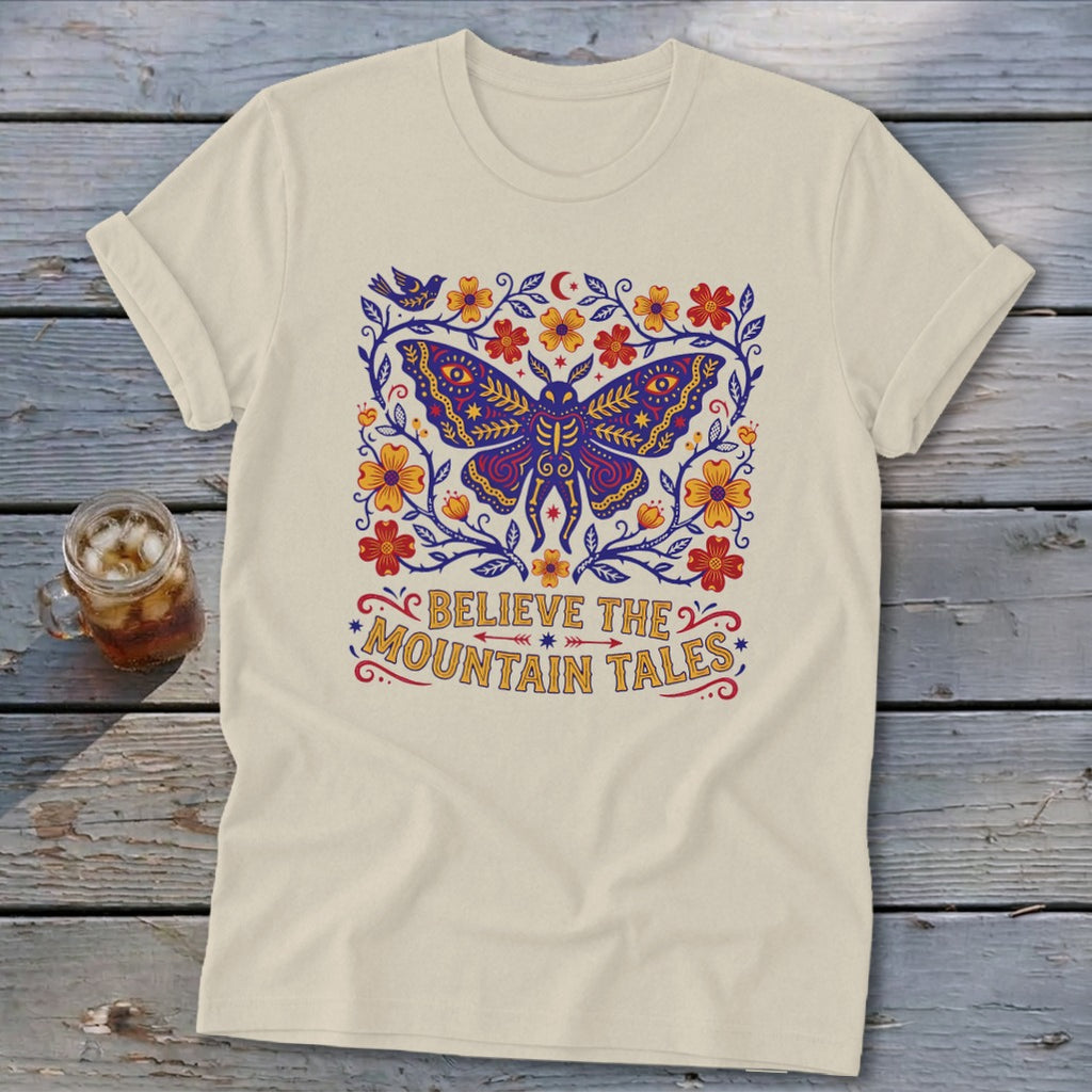 Cream t-shirt with a large purple moth surrounded by flowers and the text "BELIEVE THE MOUNTAIN TALES".