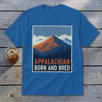 Blue t-shirt featuring a mountain graphic and the text Appalachian Born and Bred, laid on weathered wood.