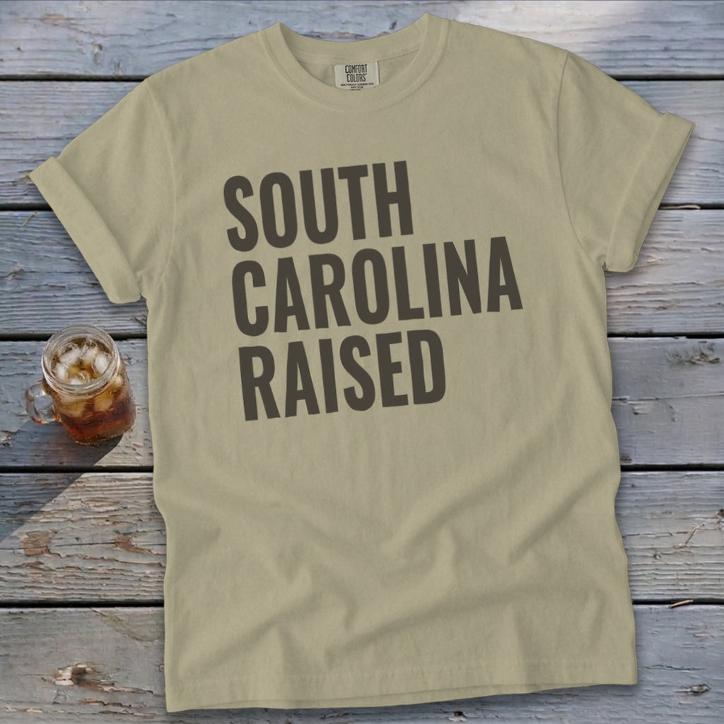 Tan t-shirt with "SOUTH CAROLINA RAISED" in dark gray text.