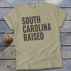 Tan t-shirt with "SOUTH CAROLINA RAISED" in dark gray text.