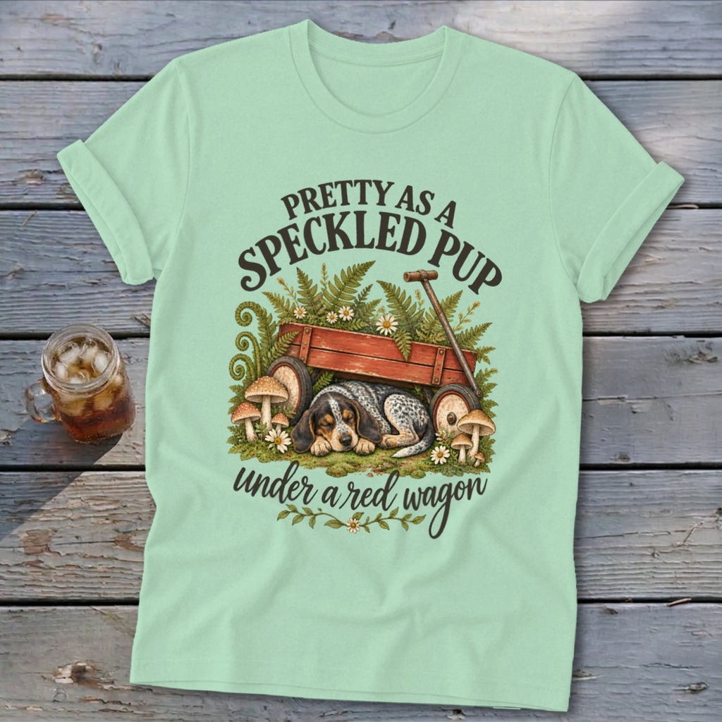 Speckled pup sleeps under red wagon with text "Pretty as a speckled pup".