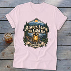 Light pink t-shirt with a graphic of a lantern and mountains, reading "Always Leave the Light On Come On In".