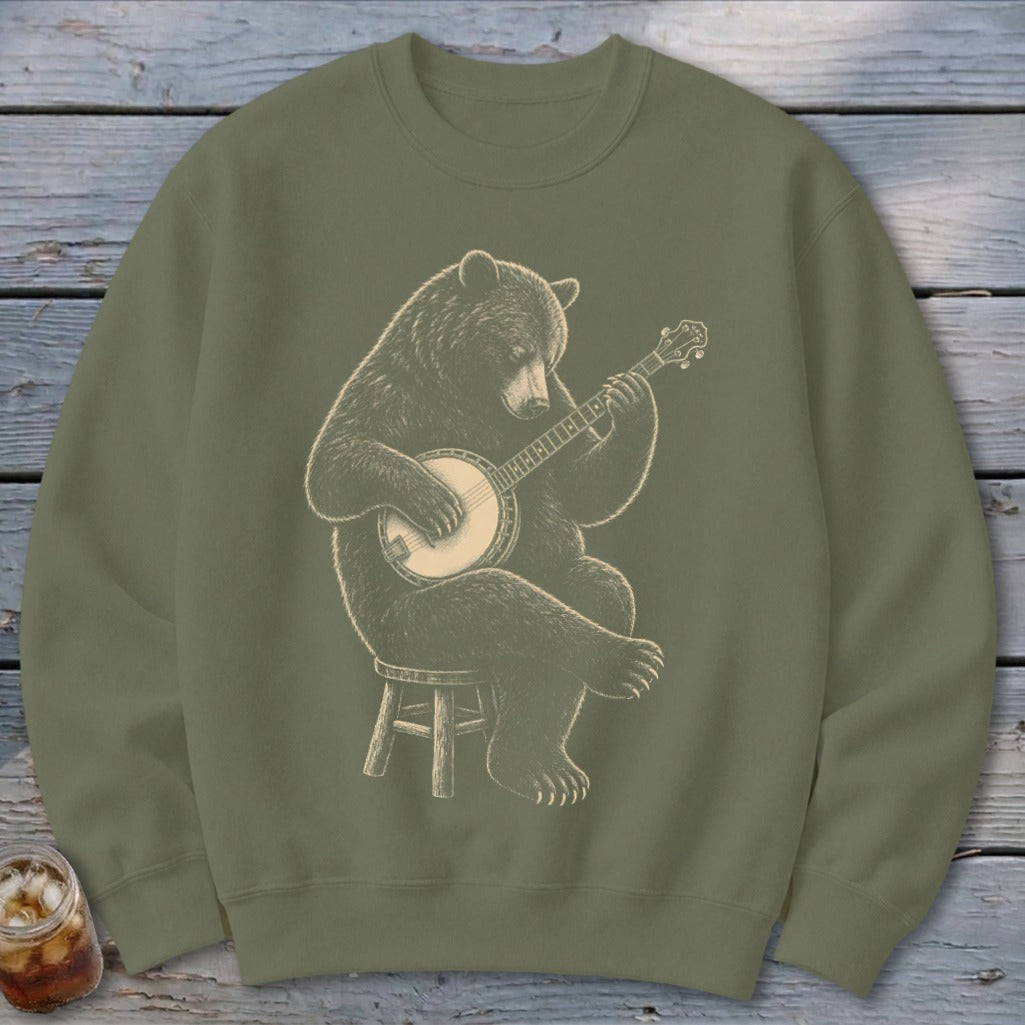 Bear sitting on stool playing a banjo, illustration on olive green sweatshirt.