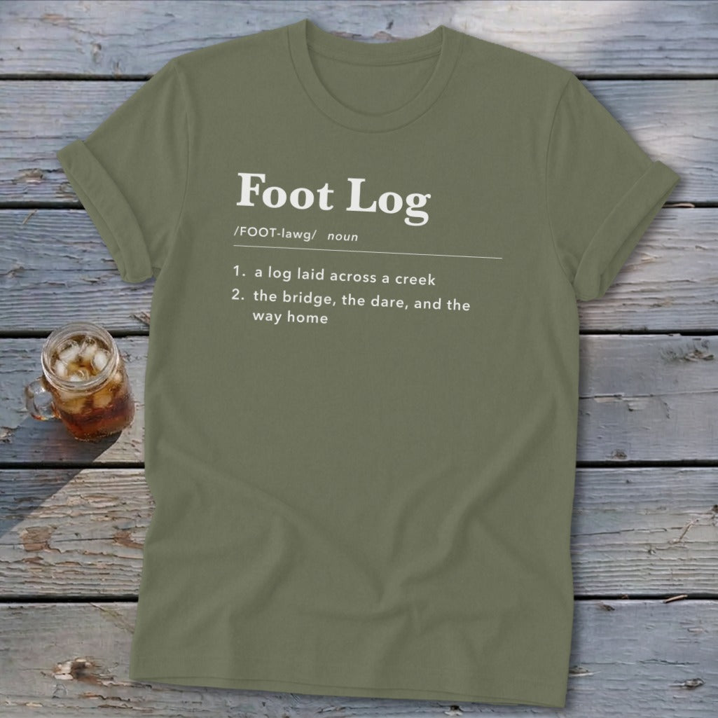 Olive green crewneck t-shirt printed with a dictionary definition for foot log on a wooden background.