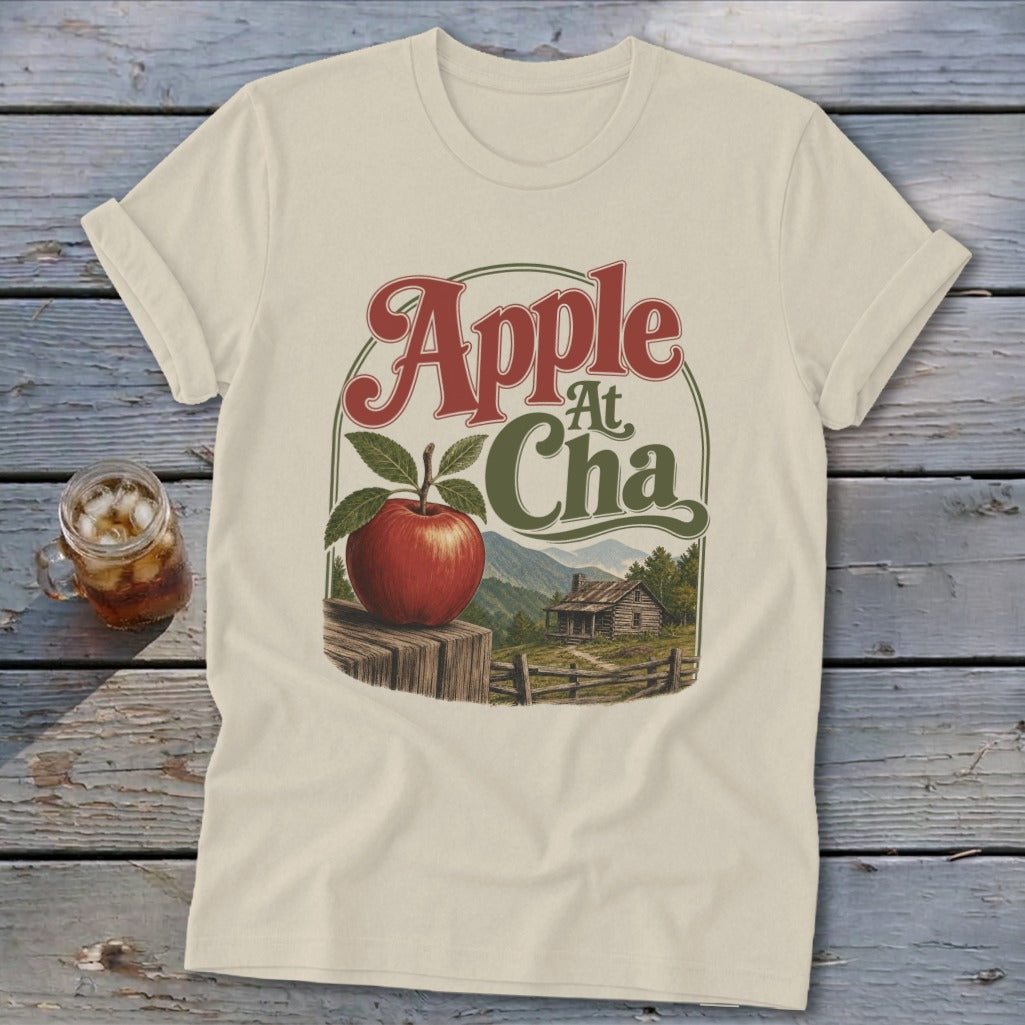 Cream t-shirt featuring a graphic of an apple on a wooden post with mountains and text Apple A Cha.