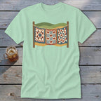 A light green t-shirt featuring a graphic of three patchwork quilts hanging on a clothesline.
