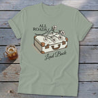 T-shirt with white vintage suitcase, flowers, and text "ALL ROADS Lead Back."