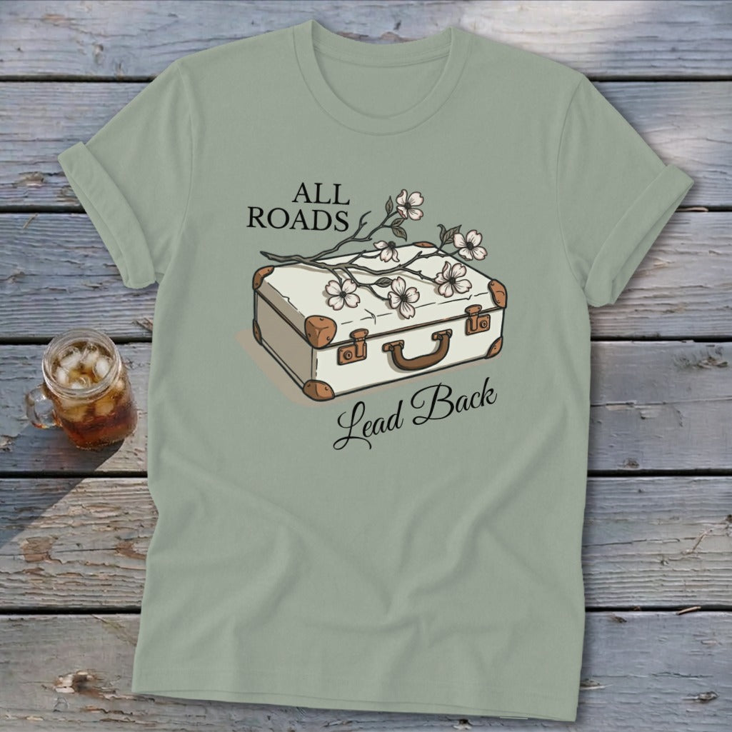 T-shirt with white vintage suitcase, flowers, and text "ALL ROADS Lead Back."