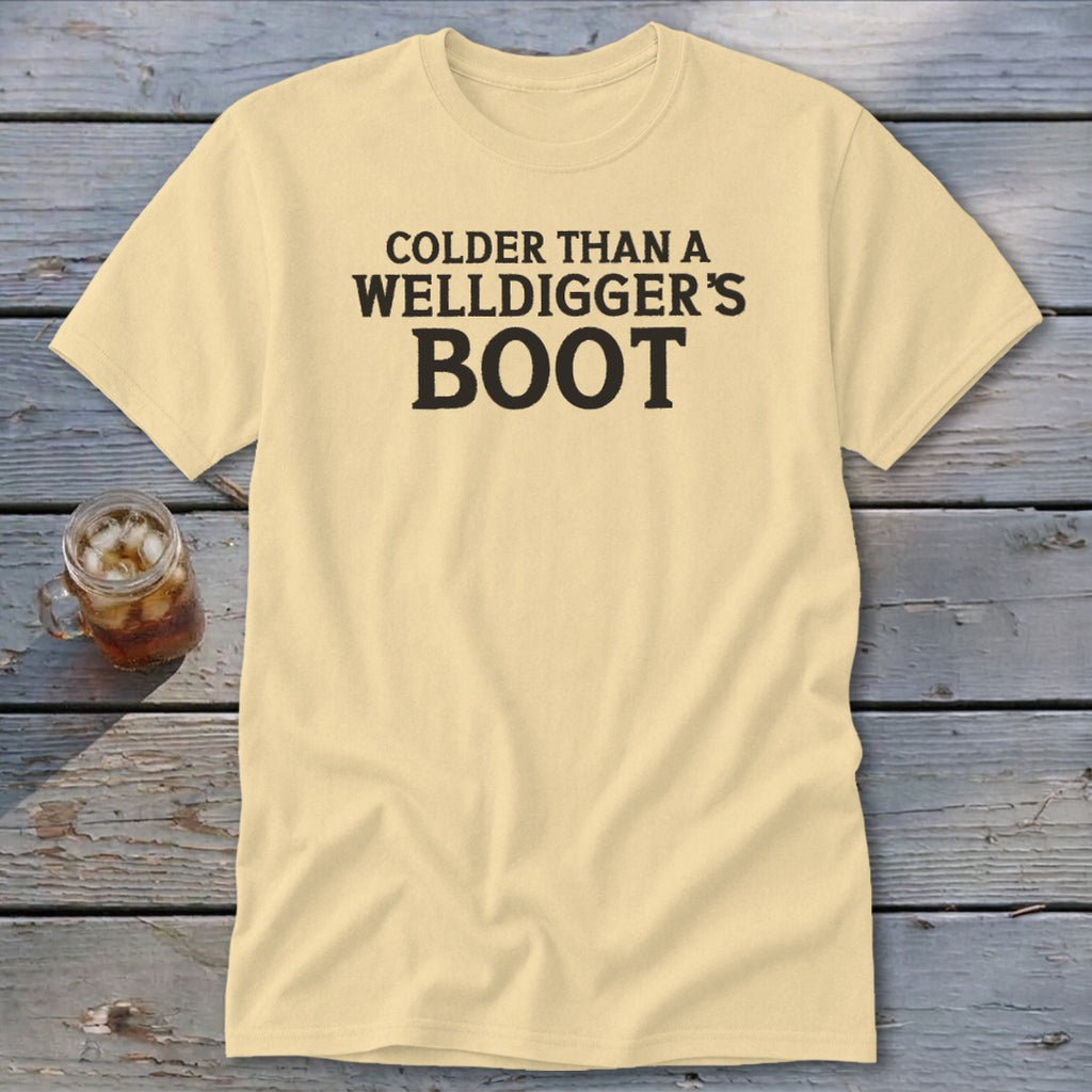 Pale yellow t-shirt with black text reading "Colder Than A Welldigger's Boot".