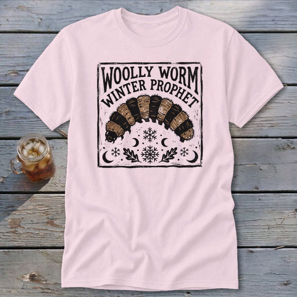 Light pink t-shirt featuring a black block-print graphic of a woolly worm with text reading Woolly Worm Winter Prophet.