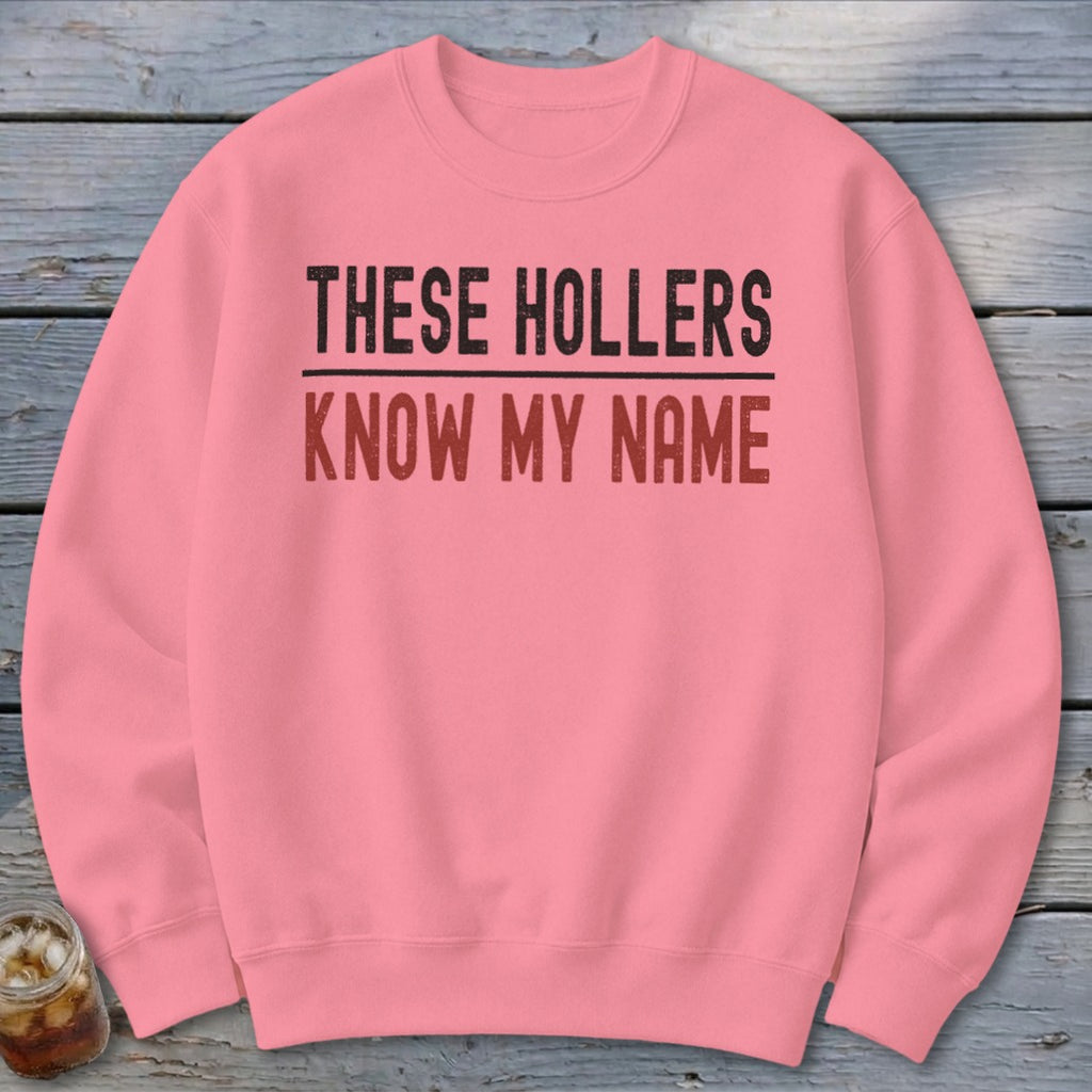 Pink crewneck sweatshirt with text "THESE HOLLERS KNOW MY NAME".