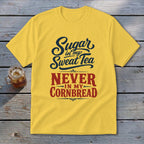 Yellow t-shirt with black and red text reading Sugar in my Sweet Tea NEVER IN MY CORNBREAD on a wooden background.