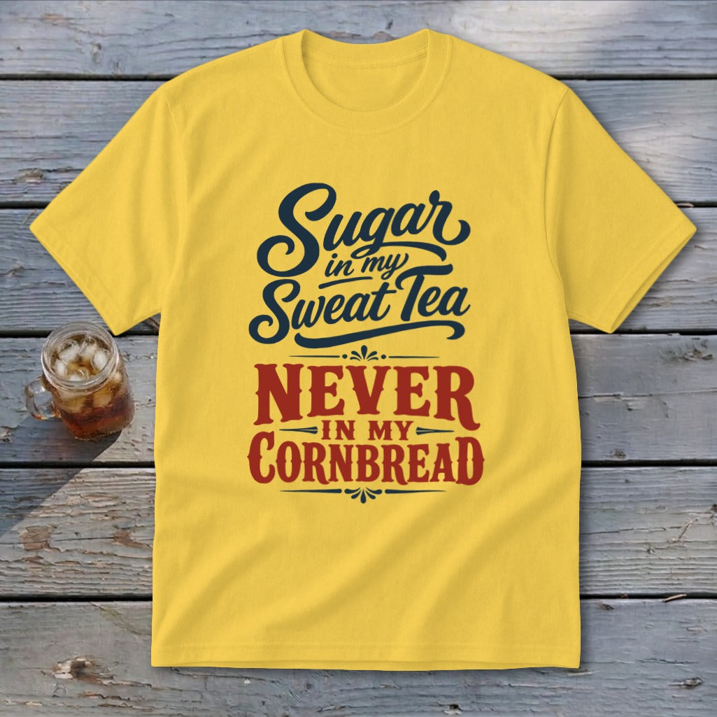 Yellow t-shirt with black and red text reading Sugar in my Sweet Tea NEVER IN MY CORNBREAD on a wooden background.