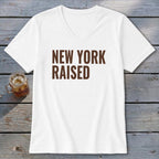 White v-neck t-shirt with "NEW YORK RAISED" text in brown.