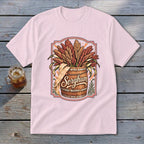 Pink t-shirt with a graphic of a wooden barrel overflowing with sorghum and the word "Sorghum."
