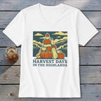 A white V-neck t-shirt featuring a graphic of stacked pumpkins with hills and sky and text reading HARVEST DAYS IN THE HIGHLANDS.