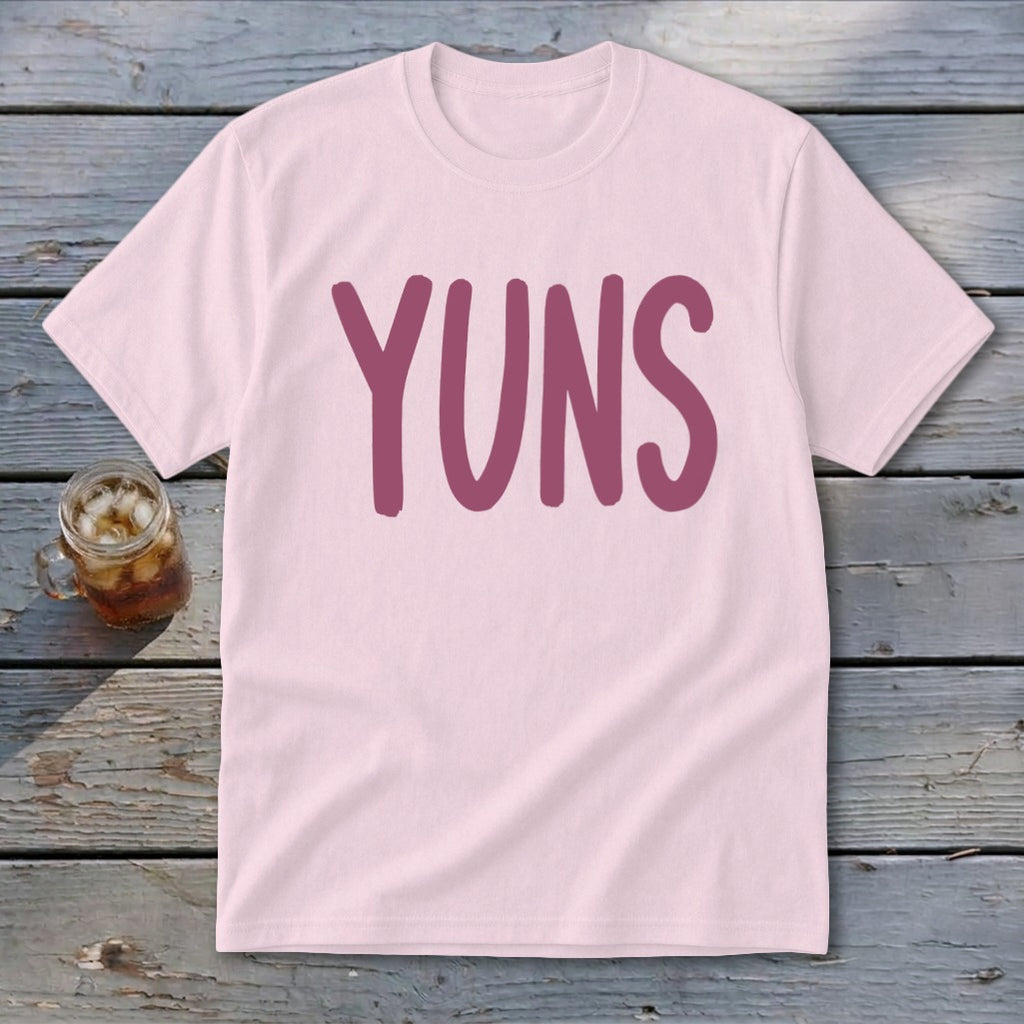 Pink t-shirt with "YUNS" in a dark pink font, next to a glass of iced tea.