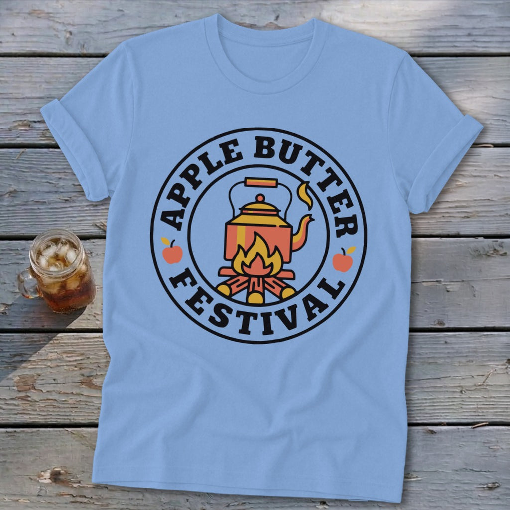 Light blue t-shirt with a circular graphic featuring a kettle over a campfire and text "Apple Butter Festival".