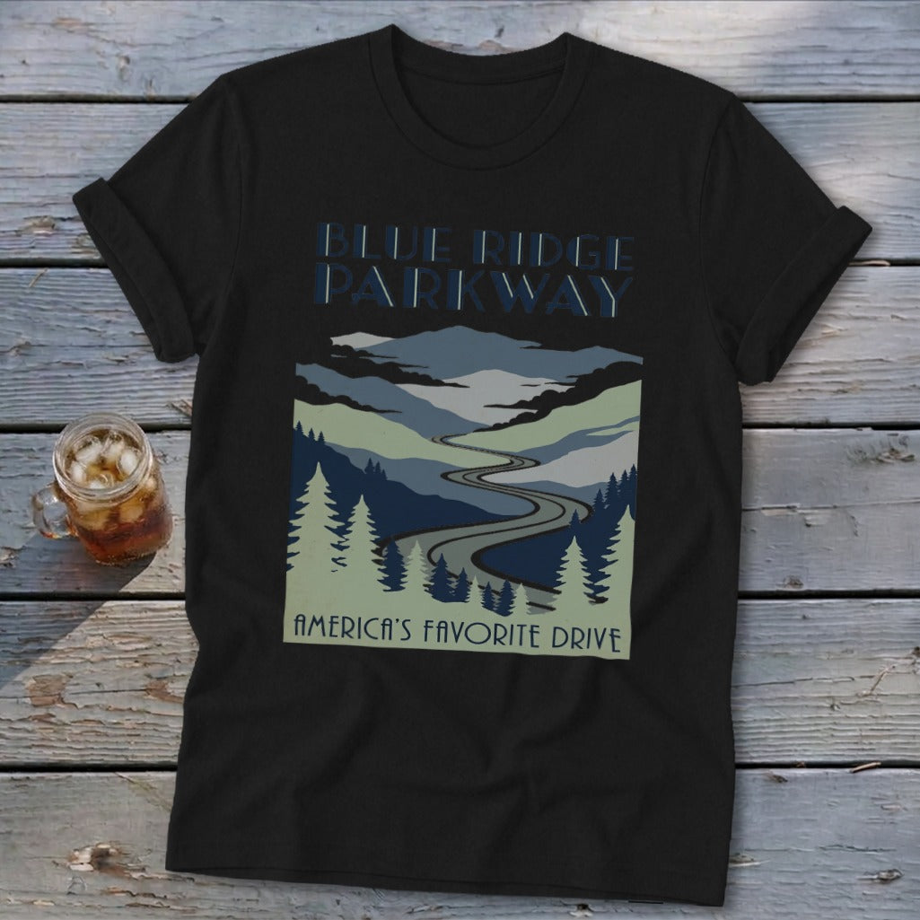A black t-shirt with a blue graphic of the Blue Ridge Parkway and a glass of iced tea on a wooden table.
