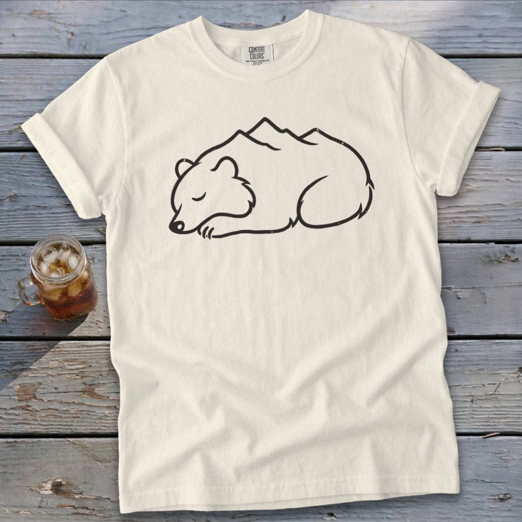 Cream t-shirt with a black outline drawing of a sleeping bear with mountains on its back.