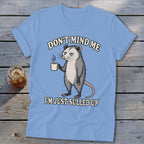 Light blue t-shirt with opossum holding coffee and text "Don't mind me I'm just sulled up."