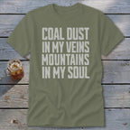 Olive green t-shirt with distressed white text reading COAL DUST IN MY VEINS MOUNTAINS IN MY SOUL.