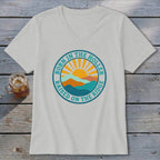 Light gray V-neck t-shirt featuring a circular graphic with mountains, a rising sun, and text.