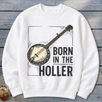 White sweatshirt with banjo graphic and text "BORN IN THE HOLLER".