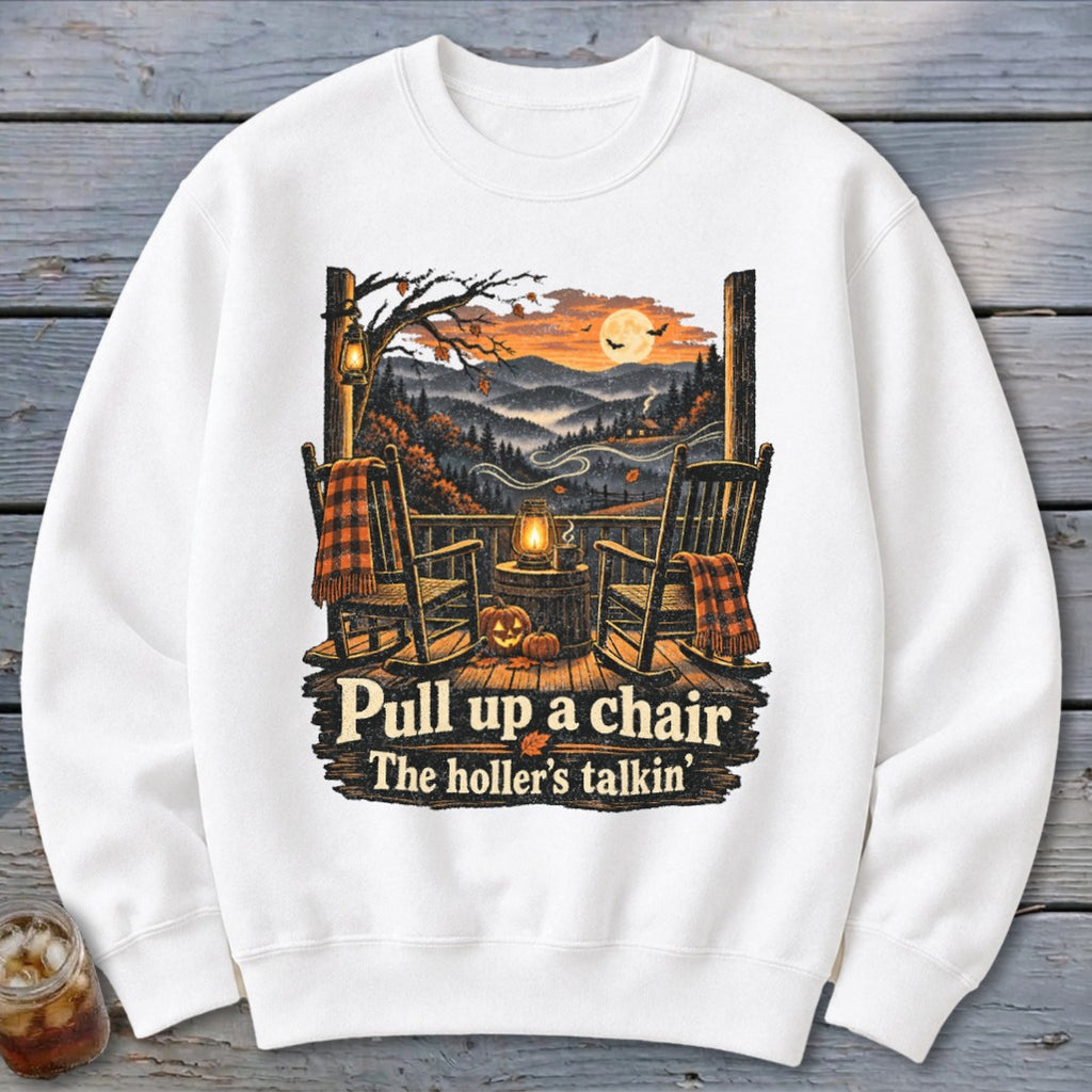 White sweatshirt with autumn porch scene, rocking chairs, pumpkins, and text "Pull up a chair The holler's talkin'".
