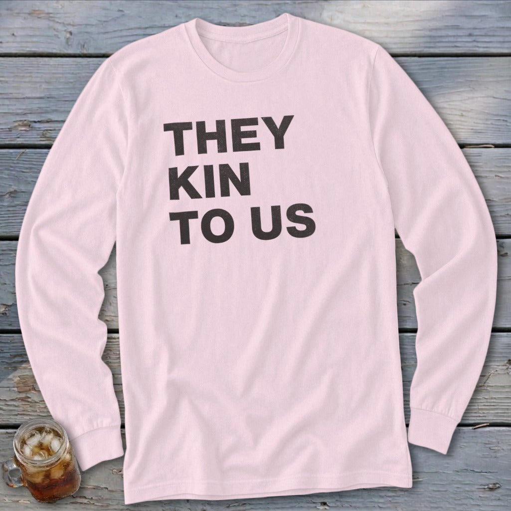 Pink long-sleeved t-shirt with black text reading "THEY KIN TO US".