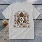 White t-shirt with brown graphic of a lantern and "ESTABLISHED IN THE HILLS".