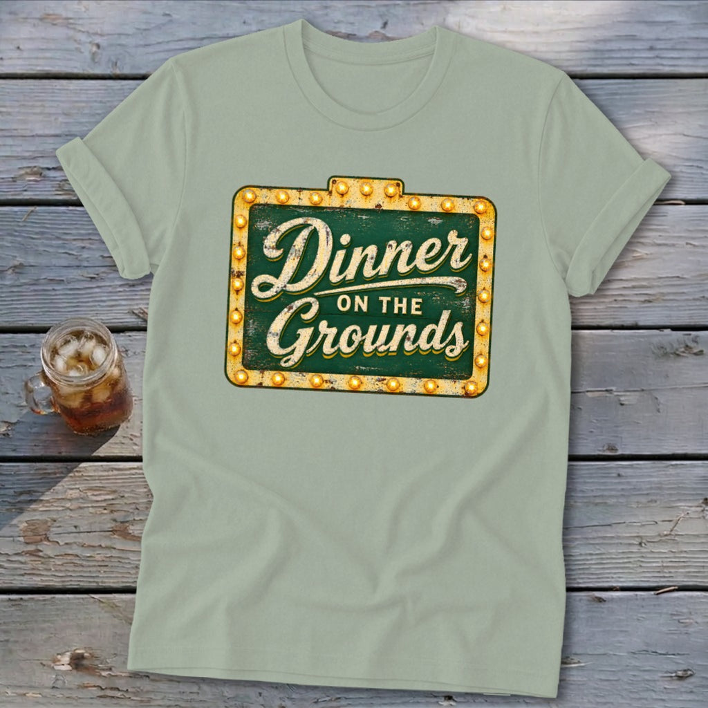Sage green t-shirt featuring a distressed vintage marquee sign with text reading Dinner on the Grounds.