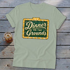 Sage green t-shirt featuring a distressed vintage marquee sign with text reading Dinner on the Grounds.