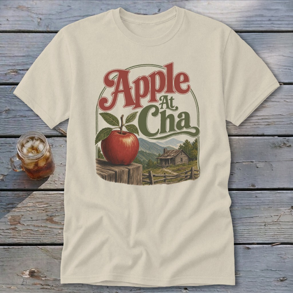 A cream-colored t-shirt displays a rustic apple illustration with the text Apple At Cha.