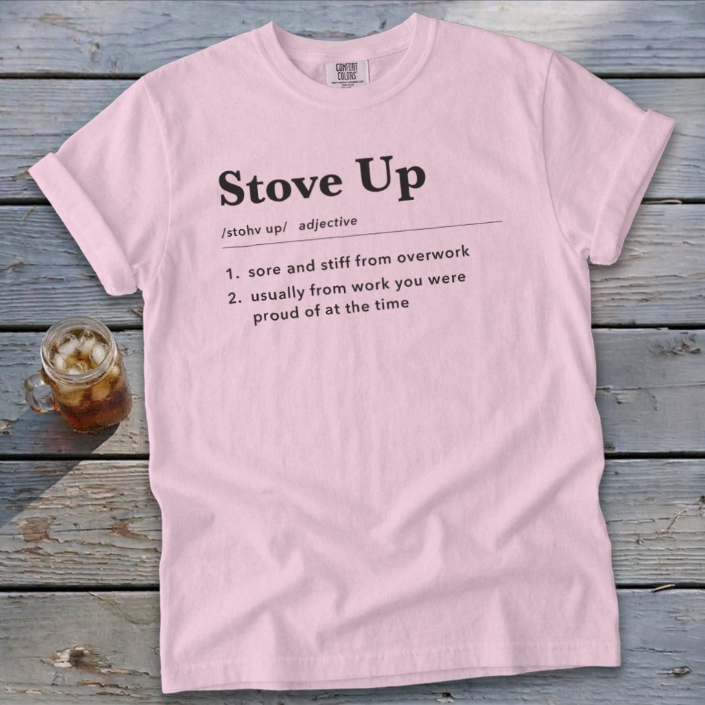 Light pink t-shirt featuring the definition of Stove Up printed on the chest, laid on weathered wood.