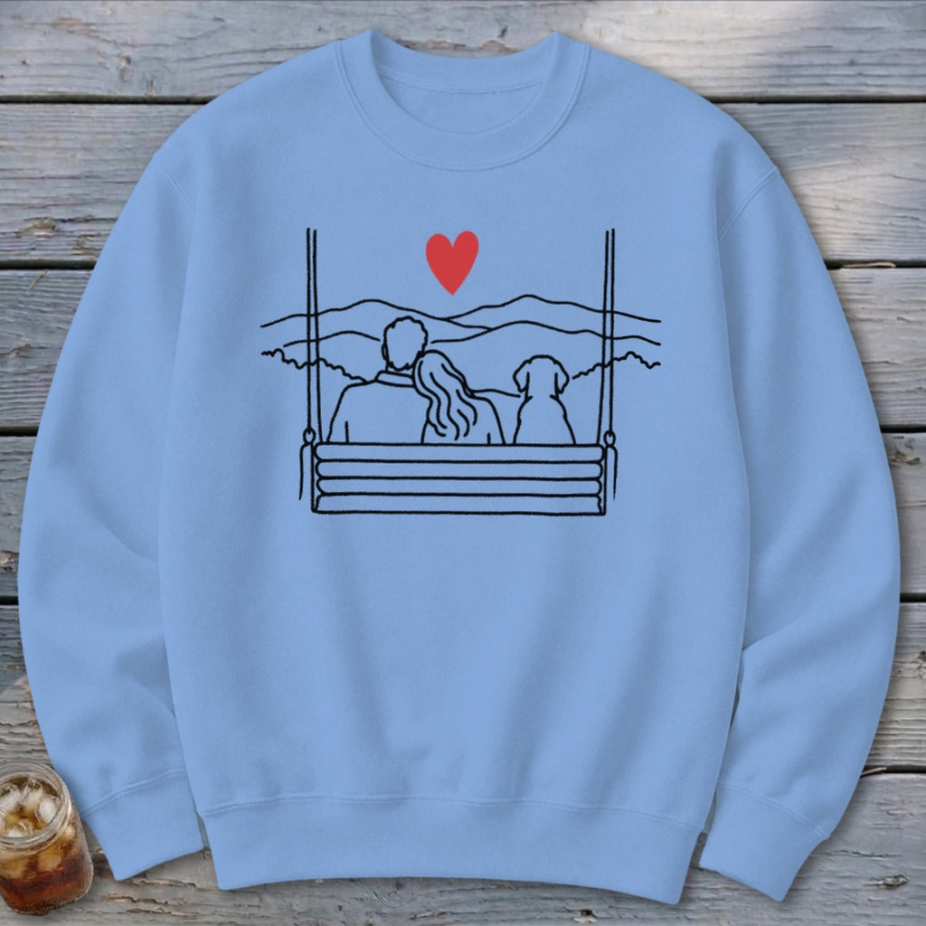 Couple and dog on a swing with a heart and mountain background.