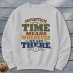 White sweatshirt with "Mountain Time Means Whenever We Get There" text and a clock.