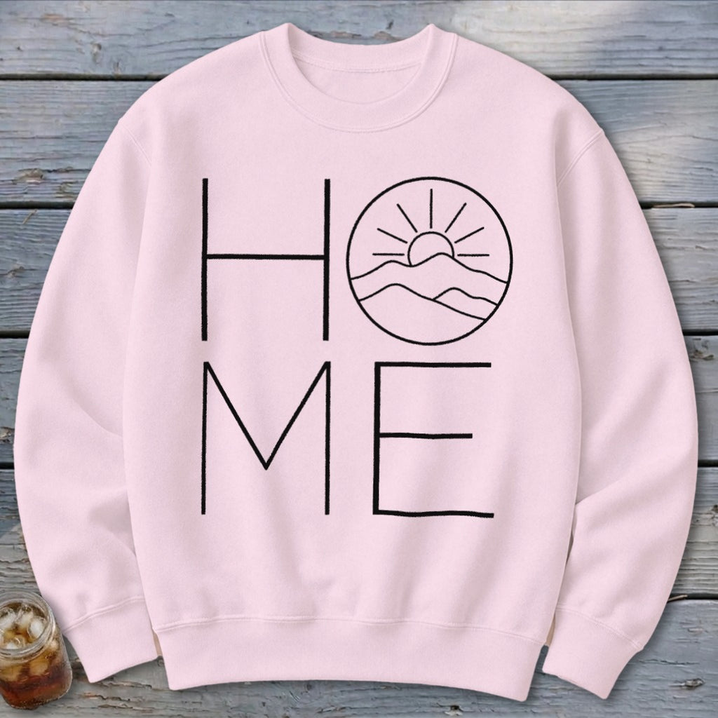 Light pink crewneck sweatshirt featuring a black graphic with the word HOME, where the O is replaced by a mountain and sun design.