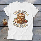 White t-shirt graphic of a layered dried apple stack cake with surrounding apples.