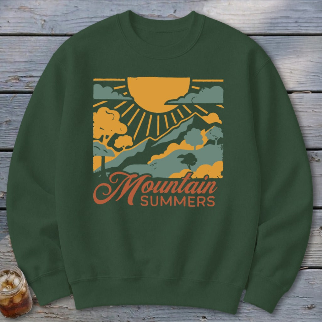 Green sweatshirt with "Mountain Summers" graphic featuring mountains, sun, and clouds.