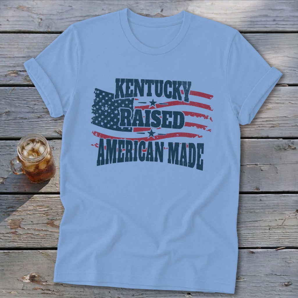 Light blue t-shirt with "Kentucky Raised American Made" graphic and distressed American flag.