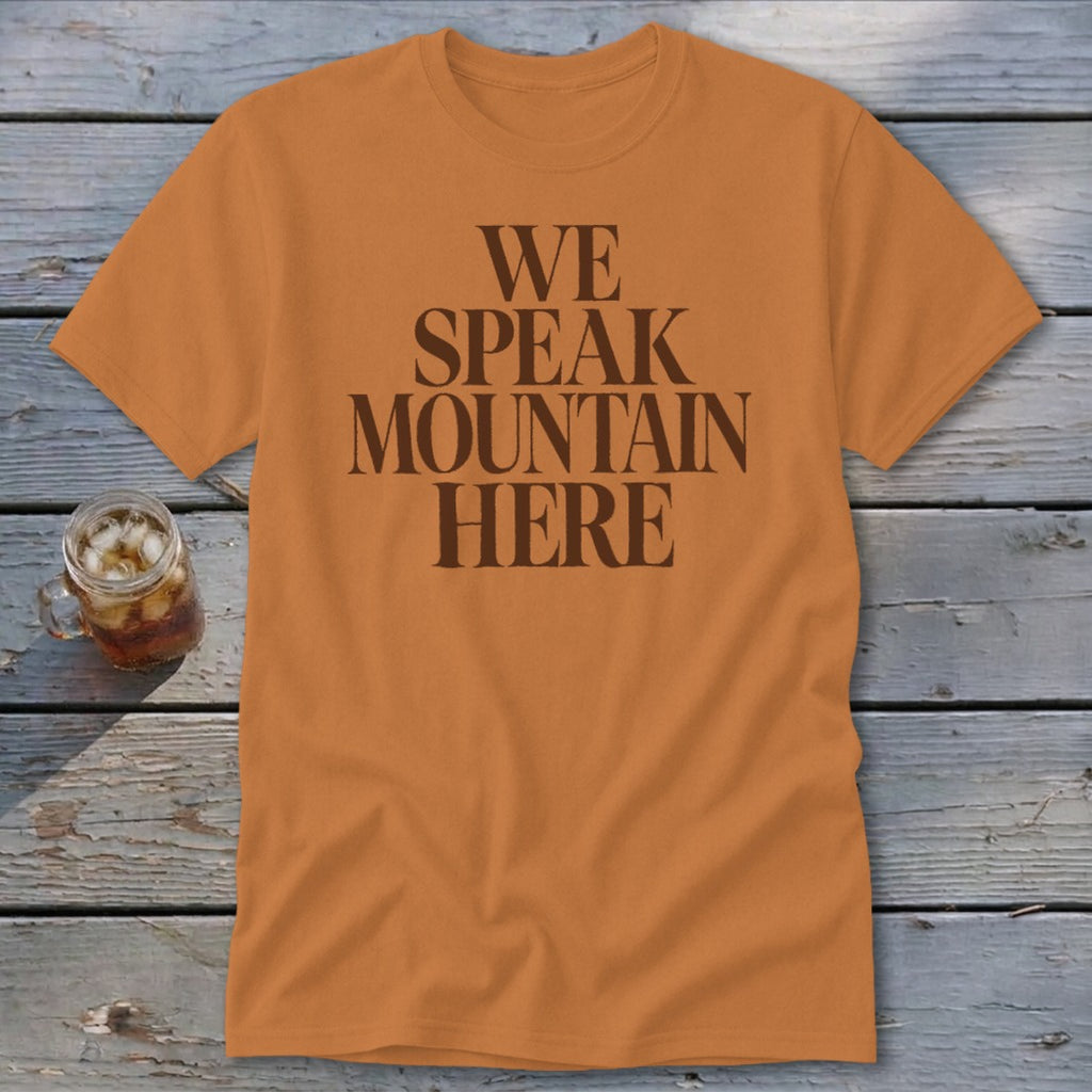 Orange t-shirt with brown text that says "WE SPEAK MOUNTAIN HERE".