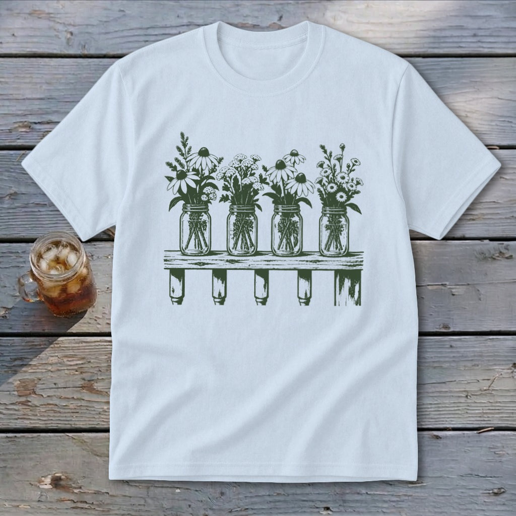 A white short-sleeved t-shirt features a green graphic of four mason jars filled with wildflowers on a shelf.