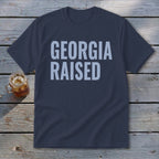Navy t-shirt with "GEORGIA RAISED" in light blue text.