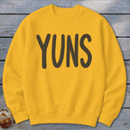 Yellow sweatshirt with "YUNS" text printed in dark brown letters.