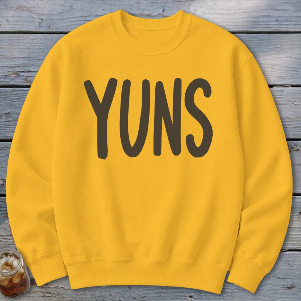 Yellow sweatshirt with "YUNS" text printed in dark brown letters.