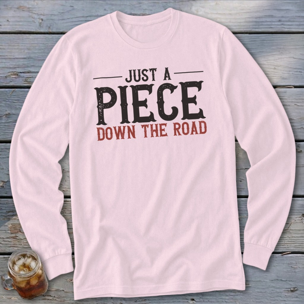 Pink long sleeve shirt with "JUST A PIECE DOWN THE ROAD" graphic.