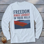 White long-sleeve t-shirt with the text FREEDOM RINGS LOUDEST IN THESE HILLS above a mountain illustration.