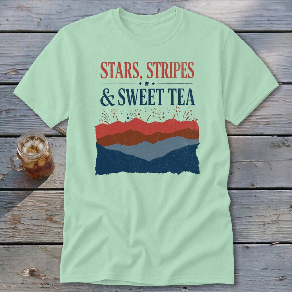 Light green t-shirt with the text "STARS, STRIPES & SWEET TEA" above a layered mountain and firework graphic.