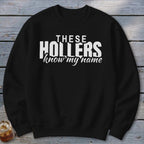 Black sweatshirt with white text "THESE HOLLERS know my name".